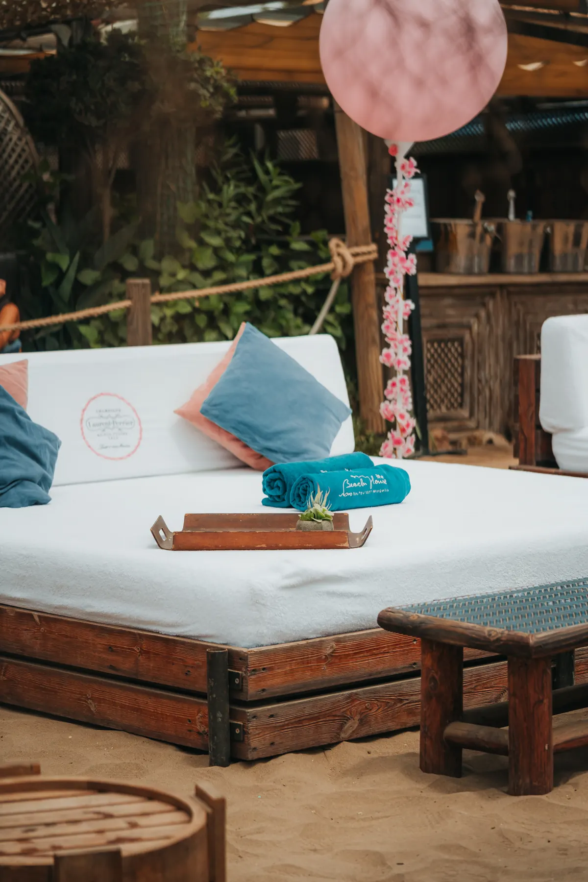 A cabana bed dressed with cushions and rolled towels