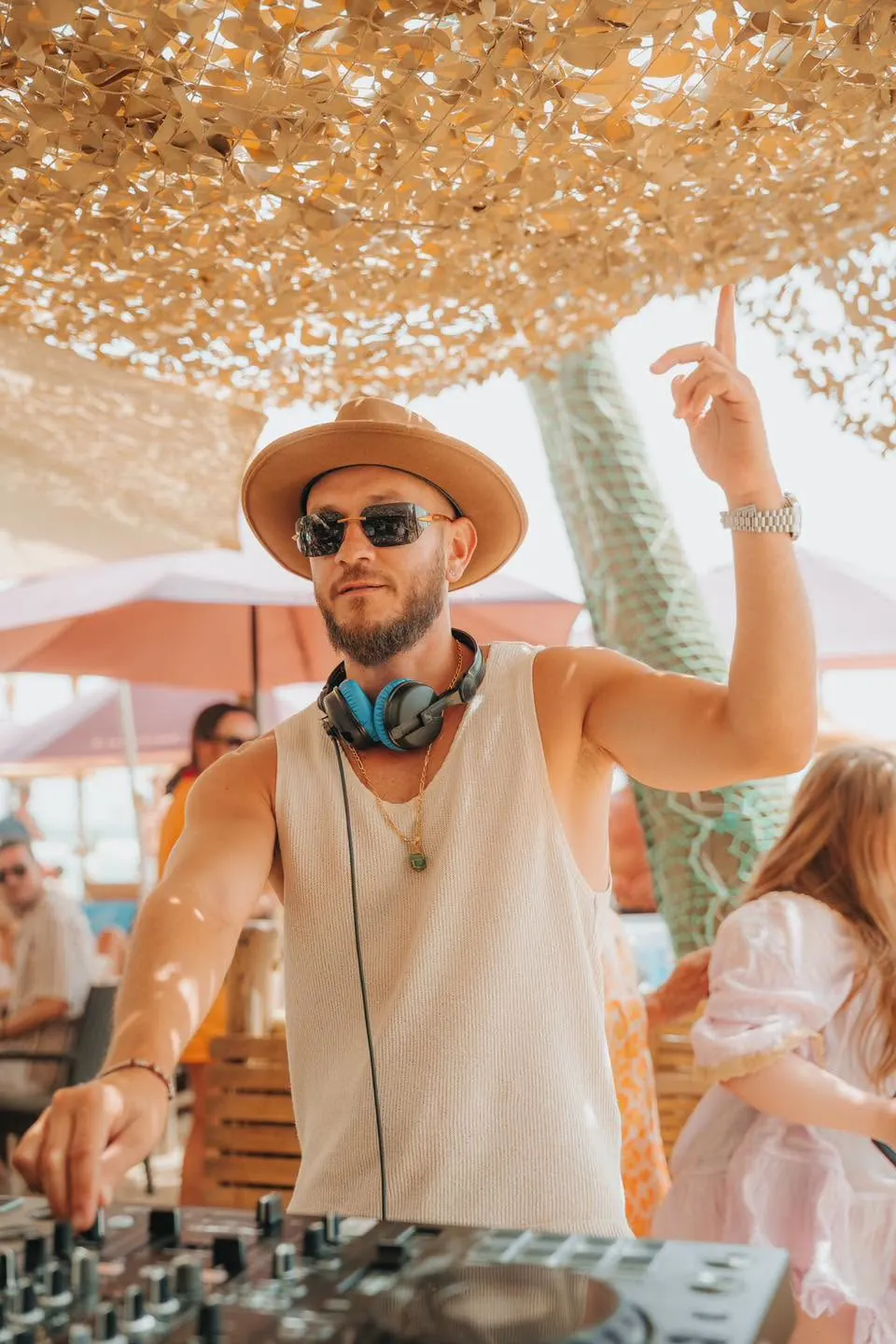 A DJ in a straw hat playing under the canopy
