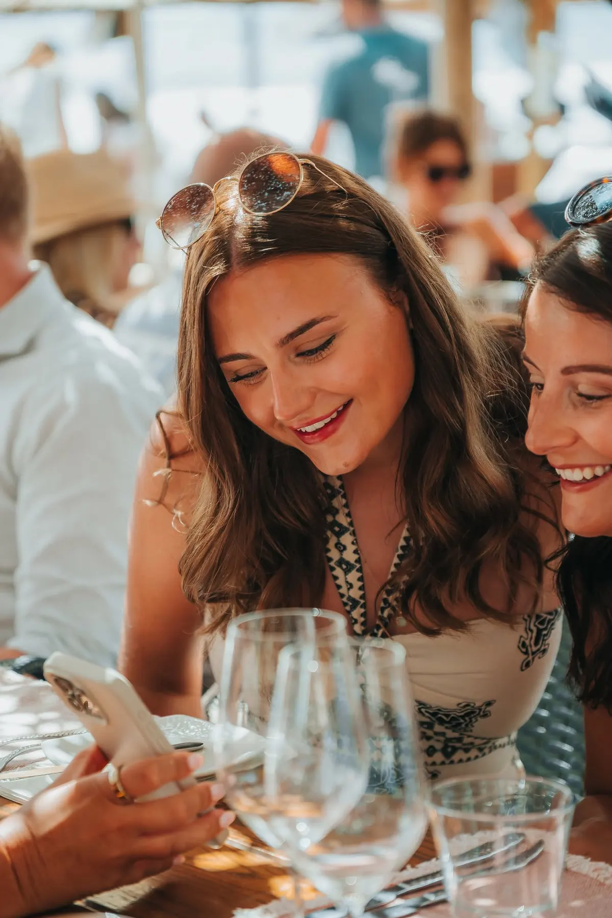 Two friends smiling at a phone during lunch
