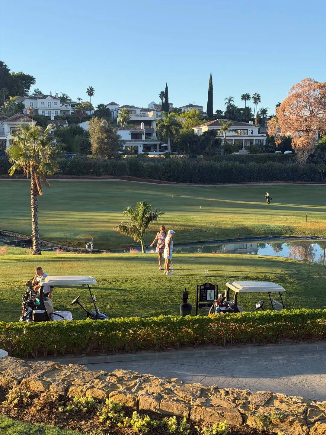 Golfers and buggies on a sunlit fairway