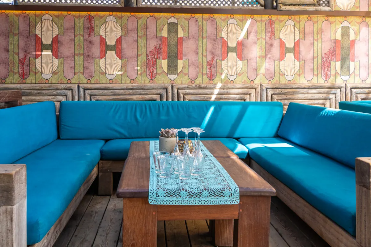 Turquoise built-in sofas and timber tables in the beach lounge