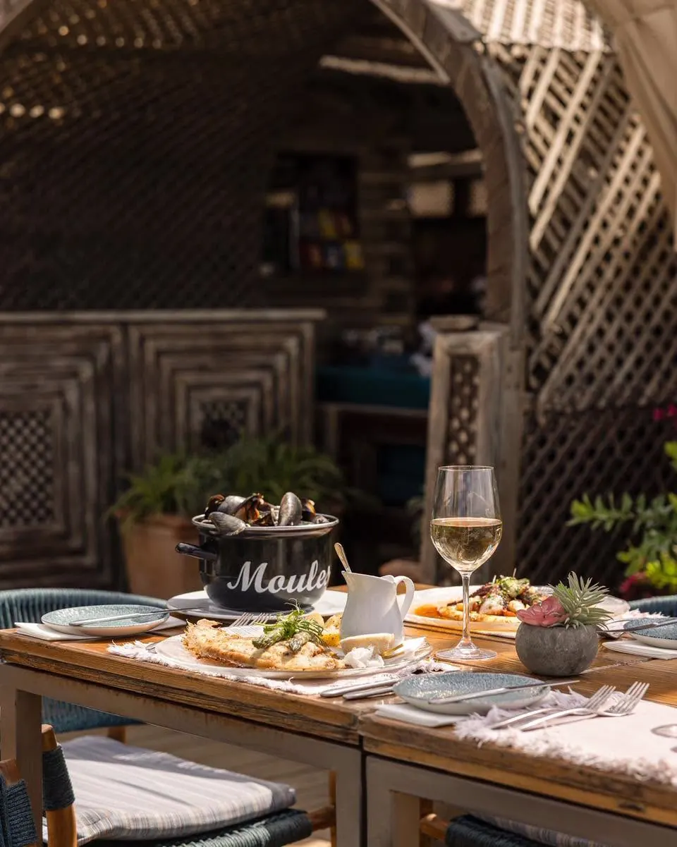 A table set with mussels and white wine in a carved timber alcove