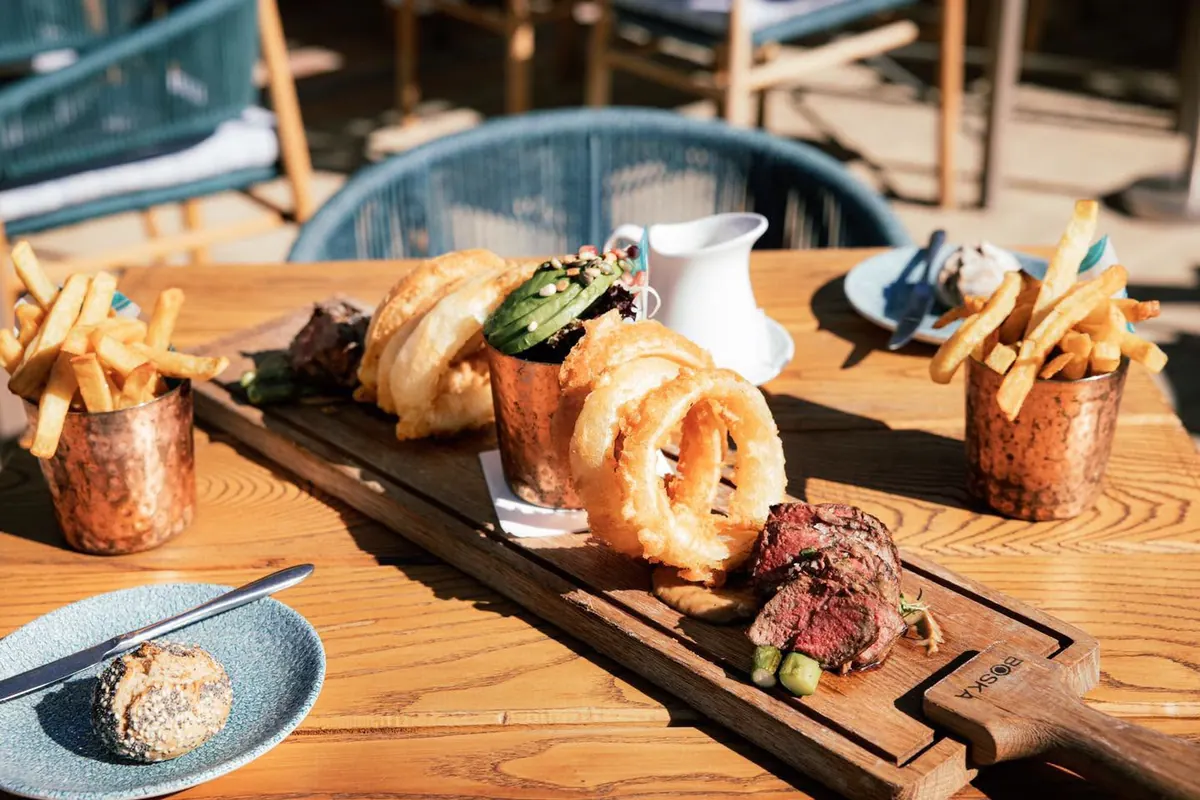 A steak sharing board with onion rings and chips