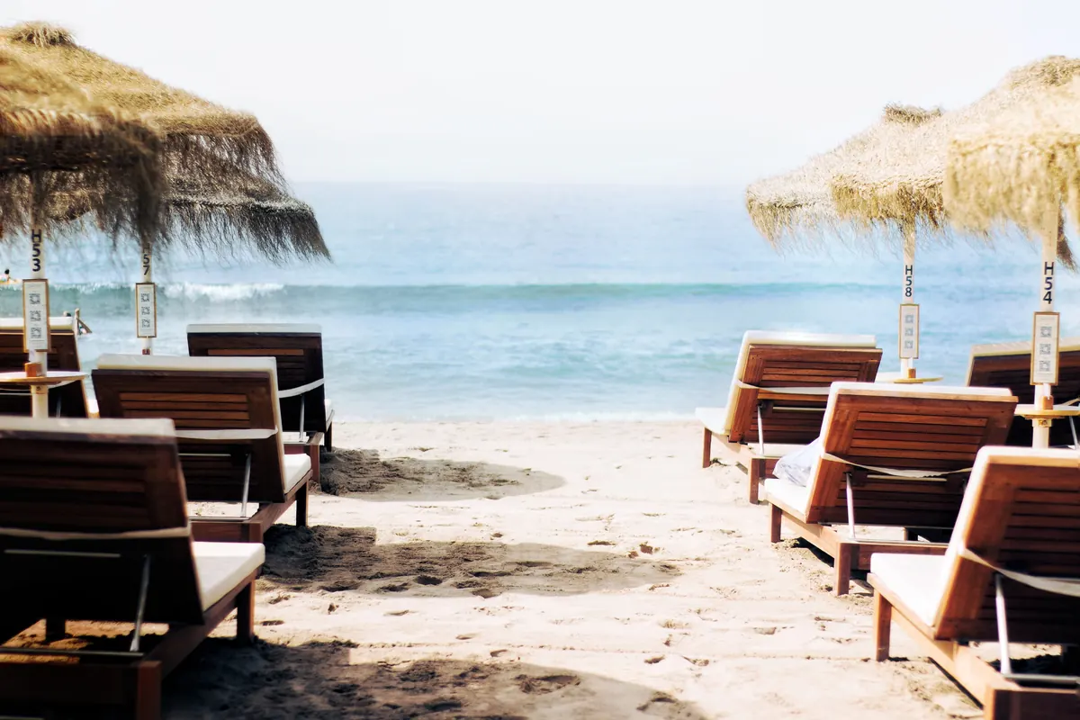 Wooden sun loungers on the sand facing the sea