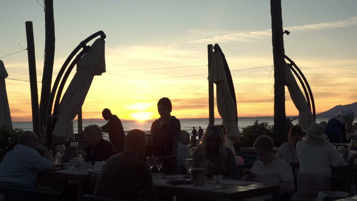 Guests silhouetted on the terrace as the sun sets over the Mediterranean