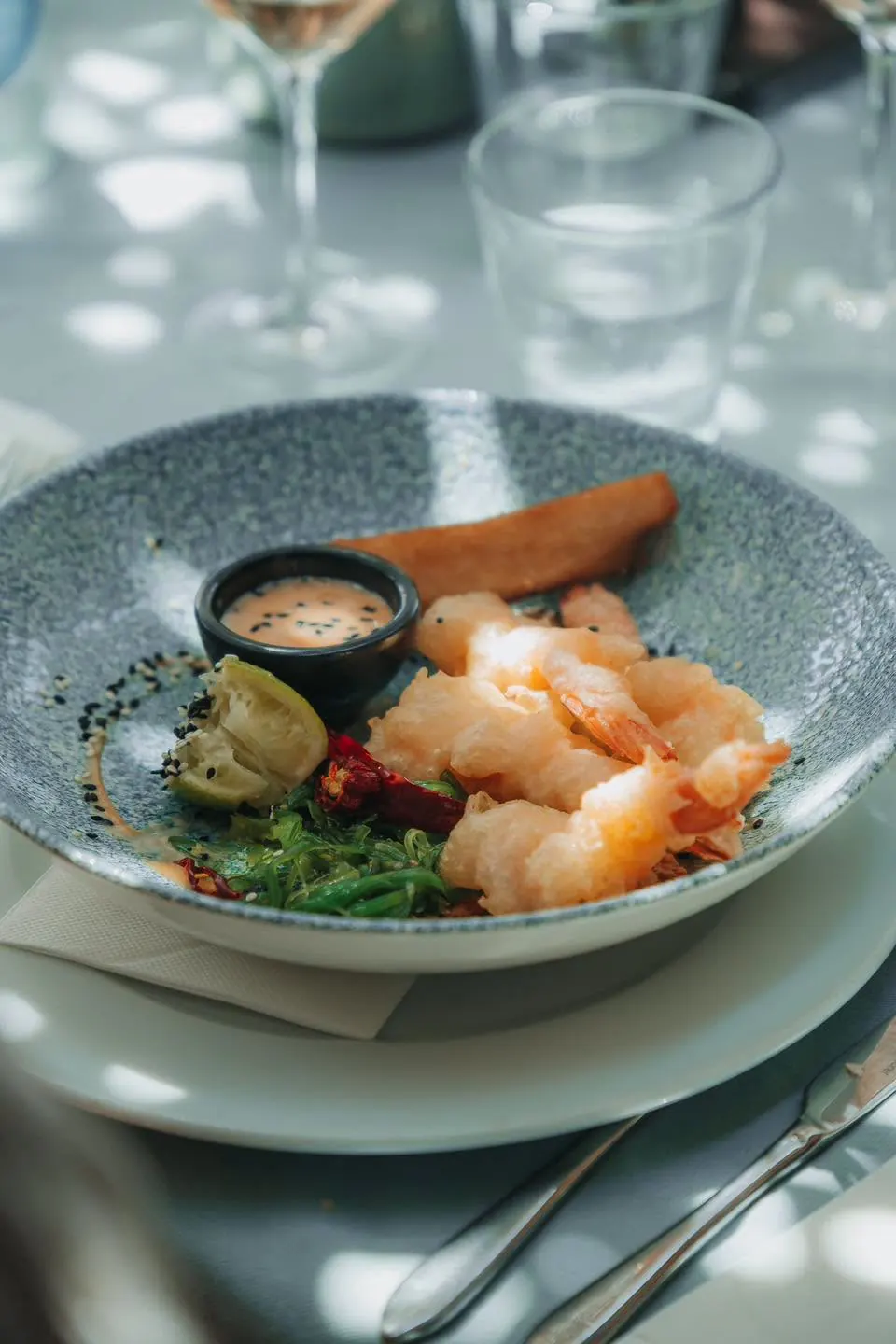 King prawns with dipping sauce on a speckled plate